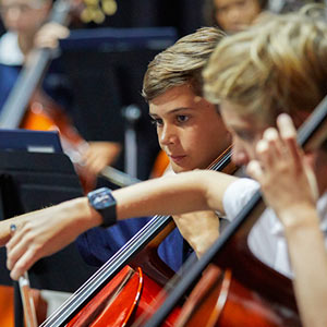 Two male students playing cello in school orchestra
