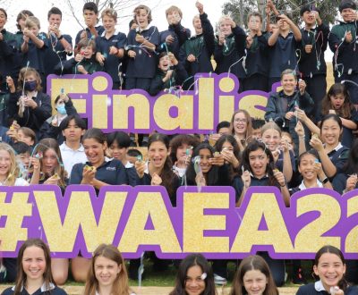 a large group of students let off streamers in celebration alongside large text signs that read 'Finalist' and '#WAEA22'