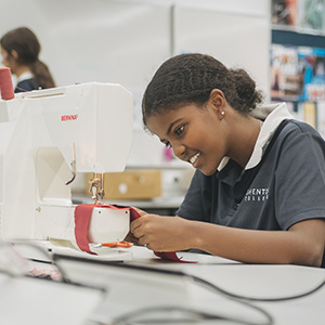 A student focusing on using a sewing machine.