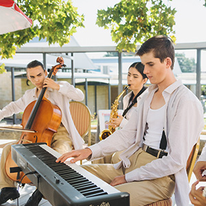 Students dressed in costumes with white collared shirts, all sitting and playing different instruments.