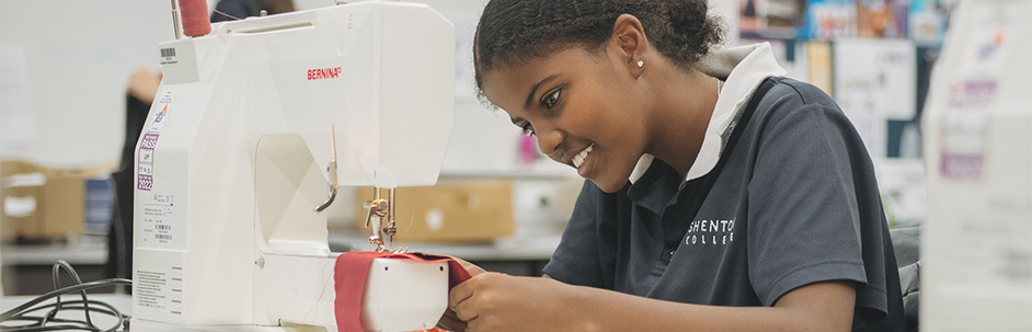 A student focusing on using a sewing machine.